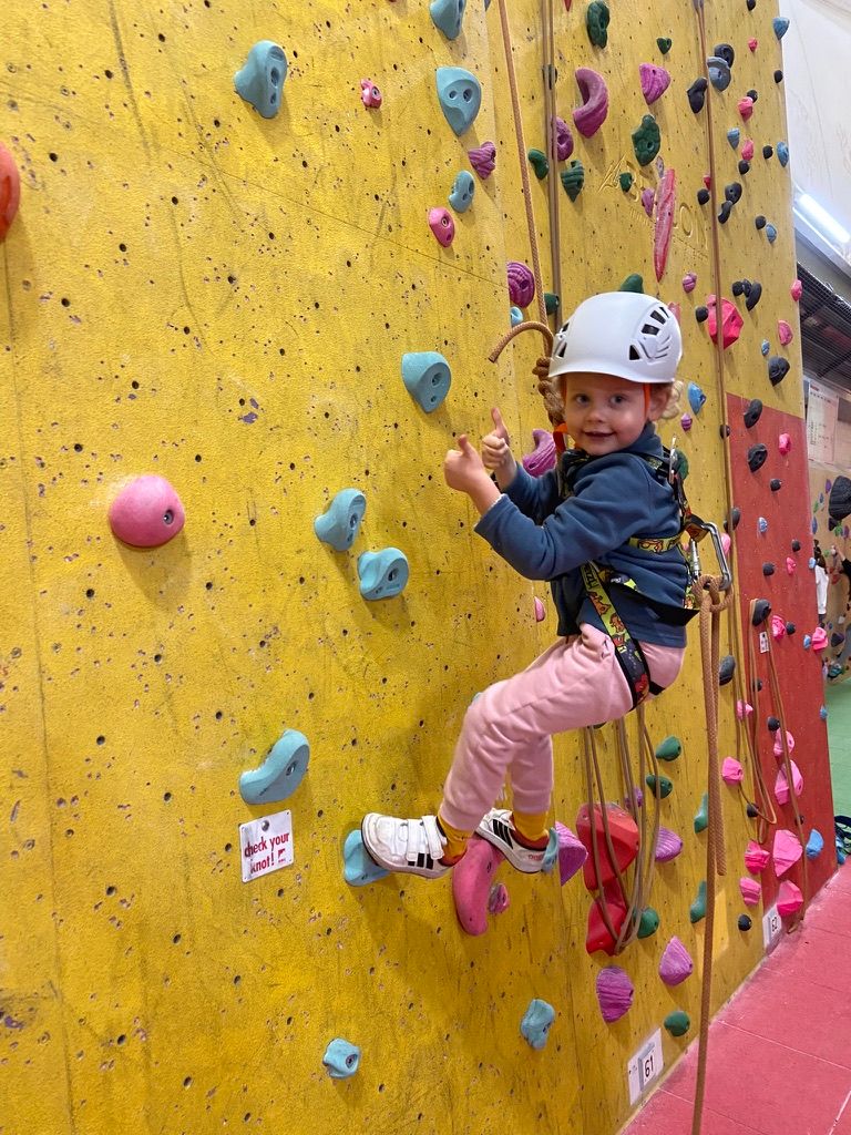 Young child smiling on an indoor climbing wall